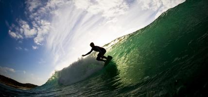 Ocean and cloudy sky with silhouette of surfer