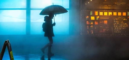 A woman walking under the rain in the dark